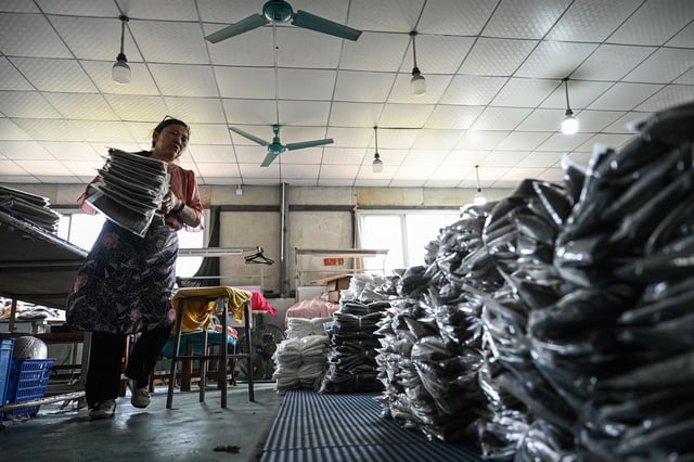An employee sorts out garments for the online Chinese e-commerce company Temu at a clothing factory in Guangzhou, in southern China's Guangdong province on April 16, 2025. China told Washington on April 16 to "stop threatening and blackmailing" after US President Donald Trump said it was up to Beijing to come to the negotiating table to discuss ending their trade war. Trump has slapped new tariffs on friend and foe but has reserved his heaviest blows for China, with 145 percent on many Chinese imports even as Beijing has retaliated with levies on US goods of 125 percent.