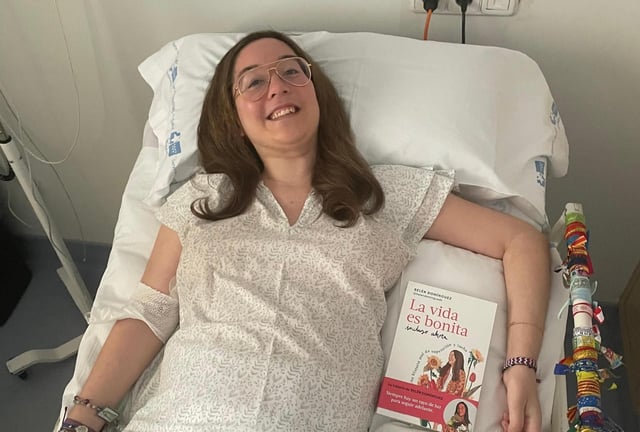 Belén Domínguez posa con su libro desde la cama de su habitación en el Hospital Ramón y Cajal.
