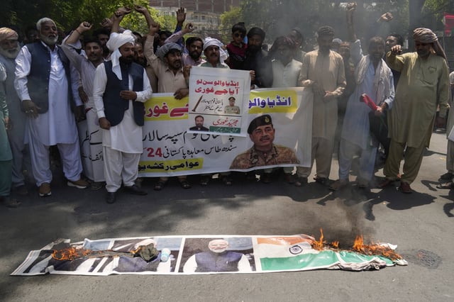 Members of the Awami Rickshaw Union chant slogans next to a burning poster of Indian prime minister Narendra Modi and a Indian flag during a demonstration against the suspension of water-sharing treaty by India with Pakistan, in Lahore, Pakistan, Sunday, April 27, 2025. (AP Photo/K.M. Chaudary)