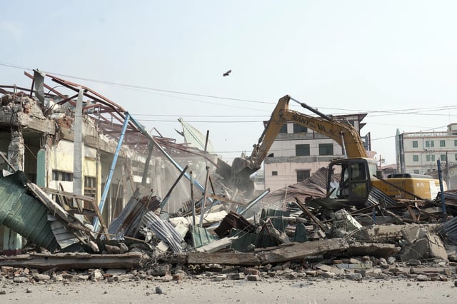 A volunteer drives a backhoe to clear debris of a building at a market, after one month of the strong earthquake in Naypyitaw, Myanmar, Monday, April 28, 2025. (AP Photo/Aung Shine Oo)