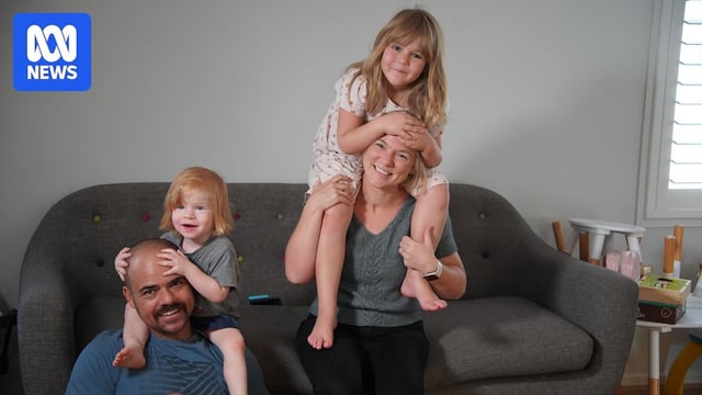 A woman with a blonde bob, smiling alongside her young family.