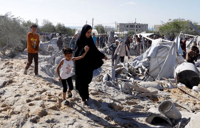 Palestinos inspeccionan los daños en el lugar de un ataque israelí a un campamento de tiendas que alberga a personas desplazadas, en Khan Younis, al sur de la Franja de Gaza.