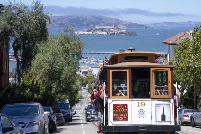 The Powell/Hyde Cable Car at Hyde Street and Chestnut Street, with Alcatraz seen in the background, runs from downtown to Fisherman’s Wharf in San Francisco and is a common attraction to tourists.
