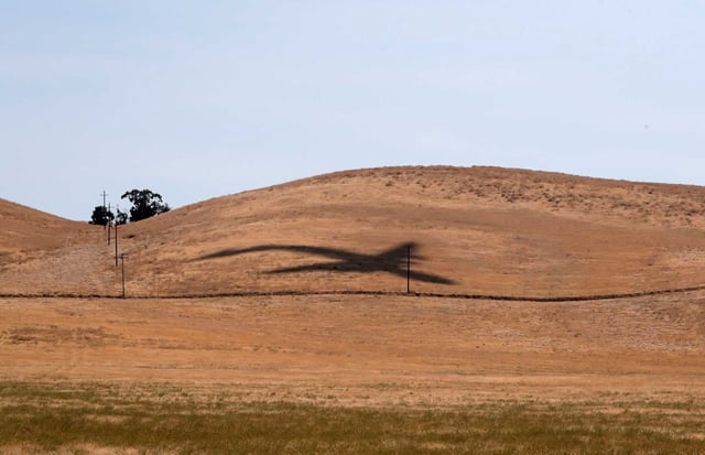 The shadow of a passing U.S. Air Force cargo aircraft is seen over ranchland just southeast of Travis Air Force Base near Fairfield on Aug. 23, 2023. 