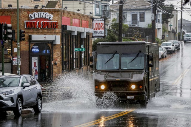 A UPS delivery truck drives through a puddle in Oakland. The company announced on Tuesday that it will eliminate 20,000 jobs and close 73 facilities by June, citing economic uncertainty and a significant reduction in business from Amazon, its largest customer.