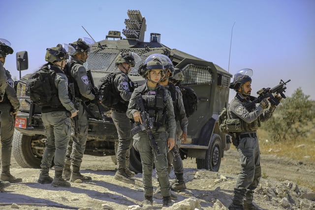 Israeli soldiers stand beside an armored vehicle during a demolition operation in Idhna, west of Hebron, West Bank, on April 28, 2025.