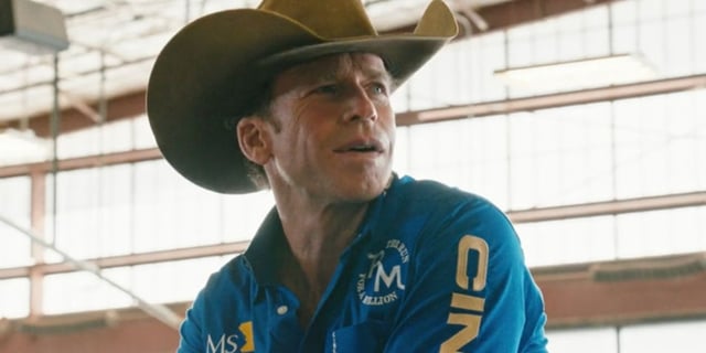 Taylor Sheridan as Travis Wheatley looking at something to his left off-screen and smiling in Yellowstone.