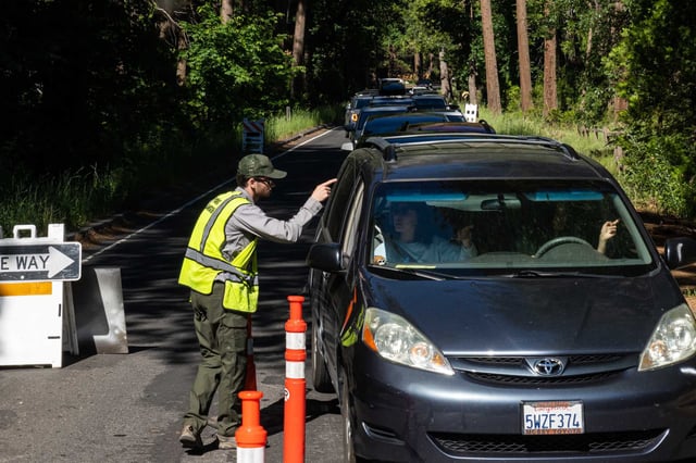 A Yosemite park ranger re-routes traffic away from Curry Village in Yosemite National Park because the parking lot is full in June 2023.