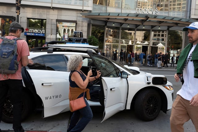Customers enter a Waymo driverless taxi at Union Square in San Francisco, California, U.S., September 28, 2024. REUTERS/Laure Andrillon/File Photo