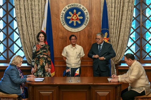 New Zealand Defence Minister Judith Collins (L) and Philippine Defence Secretary Gilberto Teodoro (R) sign a visiting forces pact on Wednesday as President Ferdinand Marcos (C) looks on