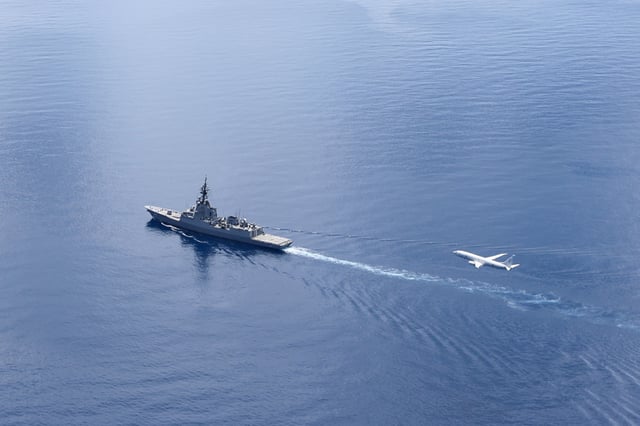 A New Zealand P-8A maritime patrol aircraft flies over the Australian destroyer HMAS Sydney on a routine surveillance flight in the South China Sea on April 24, 2025.