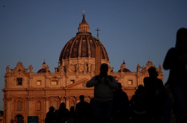People walk in front of St. Peter's Basilica in St. Peter's Square ahead of the conclave, which will be held on May 7, at the Vatican, April 30, 2025. REUTERS/Stoyan Nenov