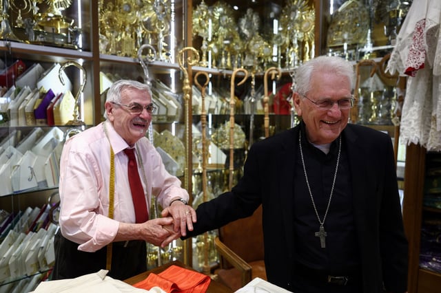 Clerical robe tailor Raniero Mancinelli jokes with Cardinal Leonardo Ulrich Steiner at his liturgical vestments shop near the Vatican, in Rome, Italy, April 29, 2025. REUTERS/Guglielmo Mangiapane