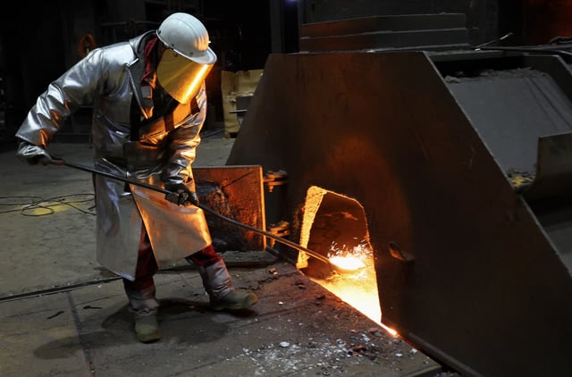 A steel worker in heat protection gear takes a sample of raw iron from Europe’s largest furnace with a daily raw iron production of 12,000 tons, at the steel plant of ThyssenKrupp in Duisburg, Germany, November 16, 2023.  REUTERS/Wolfgang Rattay/File photo