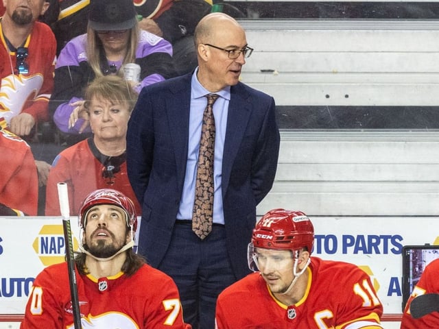 Calgary Flames head coach Ryan Huska stands on the bench during a game against the Vegas Golden Knights.
