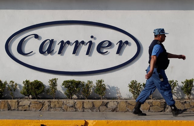 A private security guard walks past a logo of Carrier Corp outside the air conditioner plant, a unit of United Technologies Corp, in Santa Catarina, on the outskirts of Monterrey, Mexico, February 17, 2016. Picture taken February 17, 2016. REUTERS/Daniel Becerril/File photo