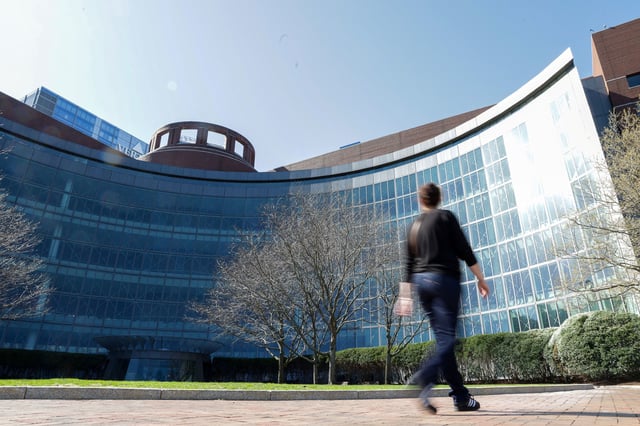 A person walks by the federal courthouse where a judge held an initial hearing April 28 in Harvard University's lawsuit seeking to block the Trump administration's freeze of billions of dollars in federal funding.