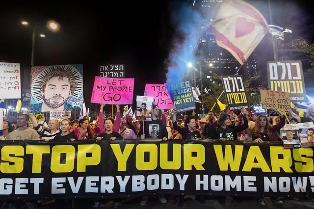 Protesters and families of the hostages hold a banner and placards during a rally, in Tel Aviv, Israel on April 6.