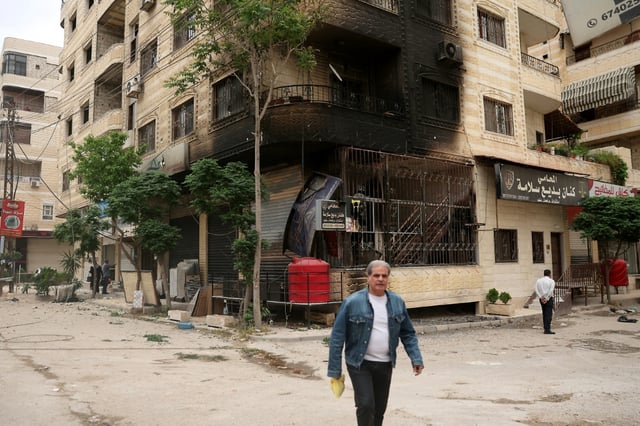 A man walks past a partially burnt building following sectarian clashes in Ashrafiyat Sahnaya near Damascus