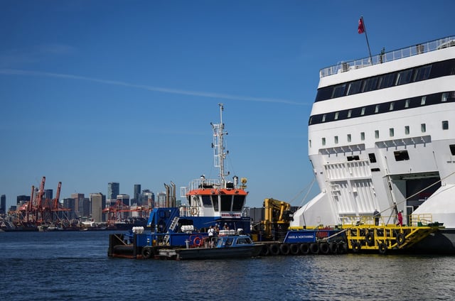 A tugboat and water taxi are seen docked at a renovated cruise ship known as a "floatel" that Woodfibre LNG planned to use to house 600 construction workers at a liquefied natural gas export facility near Squamish, at anchor in the harbour in Vancouver, on Thursday, May 9, 2024. THE CANADIAN PRESS/Darryl Dyck