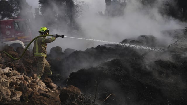 Einsatzkraft der Feuerwehr hält Wasserschlauch