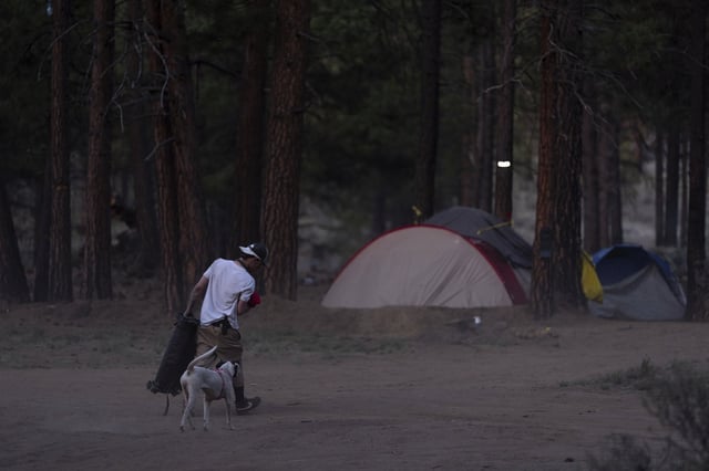 A person walks to a tent at a homeless encampment in Deschutes National Forest, Wednesday, April 30, 2025, near Bend, Ore. (AP Photo/Jenny Kane)