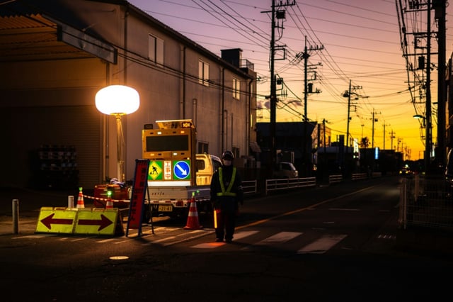 A worker in January controls the traffic at a sinkhole in Yashio, Japan