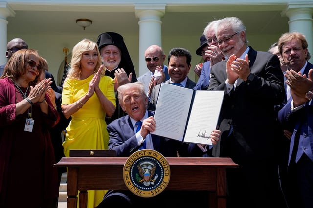 US President Donald Trump, center, displays a signed executive order at the Rose Garden of the White House in Washington, DC, US, on May 1, 2025.