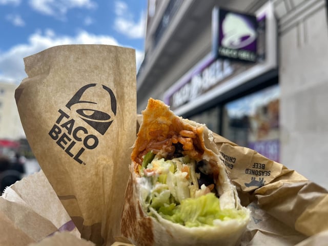 Das Taco Bell-Logo und ein Burrito sind vor einer Filiale der Kette in London zu sehen. Die US-Fastfood-Kette Taco-Bell expandiert auf den deutschen Markt. Im Sommer eröffnet in Berlin das erste Restaurant, weitere sollen folgen.