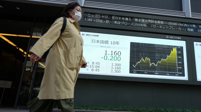A woman walks past a chart in Japan showing interest rates. Photo: Kazuhiro Nogi/AFP via Getty Images