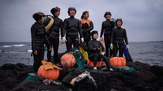 A group of Haenyeo pose for photographers as they perform a demonstration during a media event on November 6, 2015. The term "Haenyeo," or "sea women," refers to women who use free-diving techniques to retrieve shell fish from the sea floor.