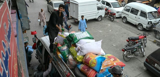 Des habitants chargent des sacs de nourriture sur le toit d'une camionnette au marché de Muzaffarabad, le 2 mai 2025 au Cachemire pakistanais