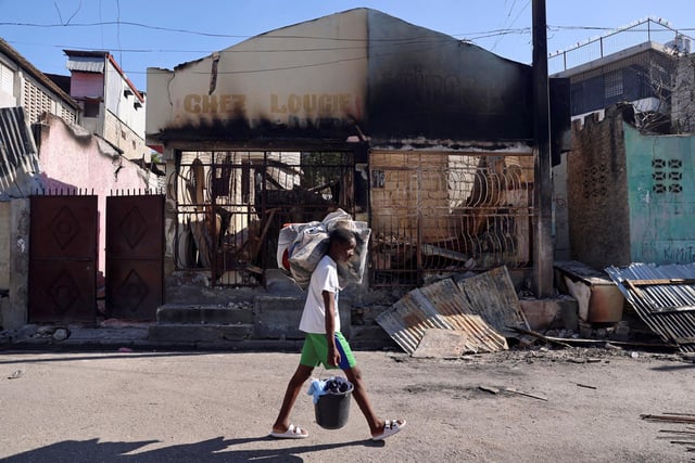 A man carries his belongings as he flees home following attacks by armed gangs, many grouped behind an alliance known as Viv Ansanm, in the Poste Marchand neighborhood of Port-au-Prince, Haiti, on Dec. 9, 2024. 