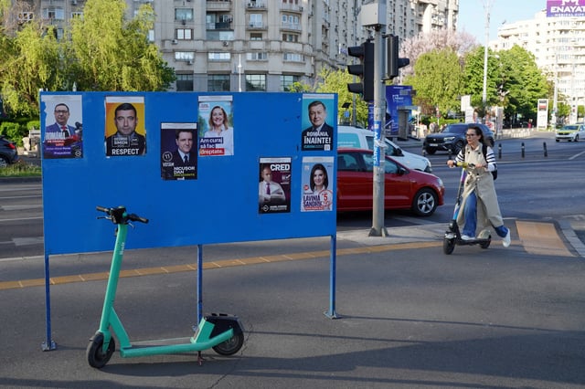 A woman rides a scooter near electoral posters ahead of Romania's presidential elections, in Bucharest, Romania, April 29, 2025. REUTERS/Andreea Campeanu/File Photo
