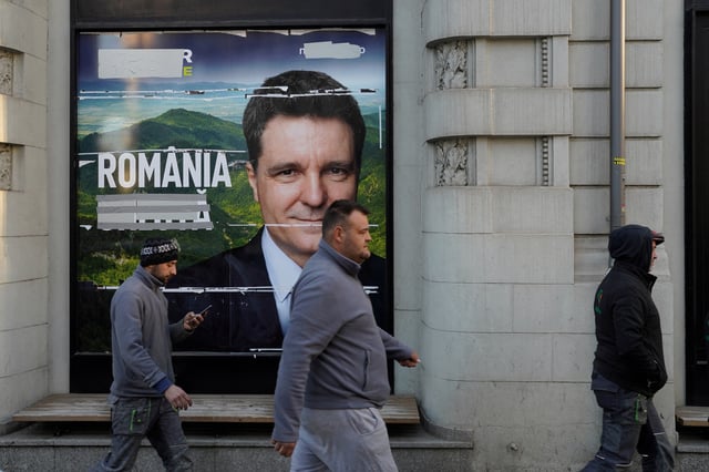 Three men pass by a poster of Nicusor Dan ahead of Romania's presidential elections, in Bucharest, Romania, April 29, 2025. REUTERS/Andreea Campeanu/File Photo