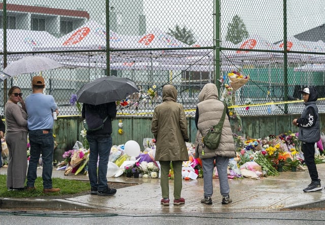 Members of the Filipino community gather at a memorial site for the victims of an incident where a car drove through a crowd killing multiple people in Vancouver, Monday, April 28, 2025. Tents from the Lapu Lapu festival remain up behind police lines. 