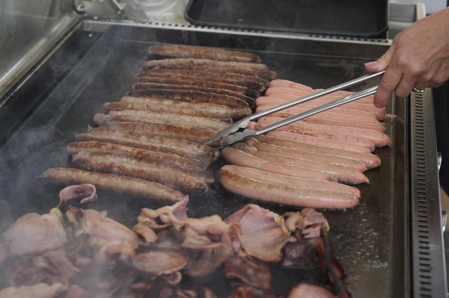 A volunteer cooks sausages on a BBQ outside a polling booth at Sydney's Bondi Beach, Saturday, May 3, 2025. (AP Photo/Mark Baker)