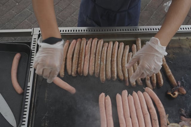 A volunteer cooks sausages on a BBQ outside a polling booth at Sydney's Bondi Beach, Saturday, May 3, 2025. (AP Photo/Mark Baker)