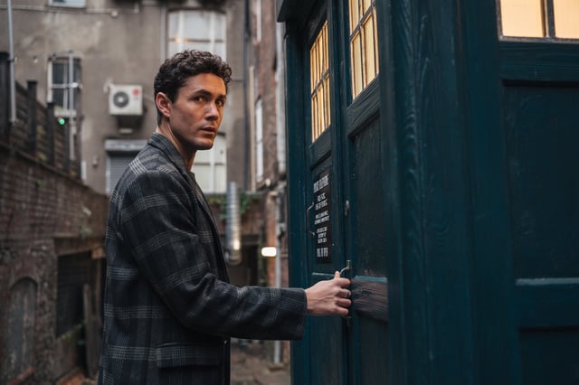 Conrad holding the handle to the Tardis doors.