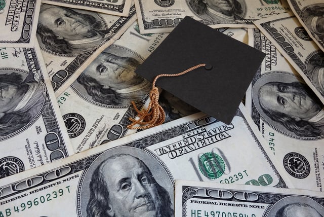 Stock image/file photo: A mortarboard laid over U.S. Dollars.
