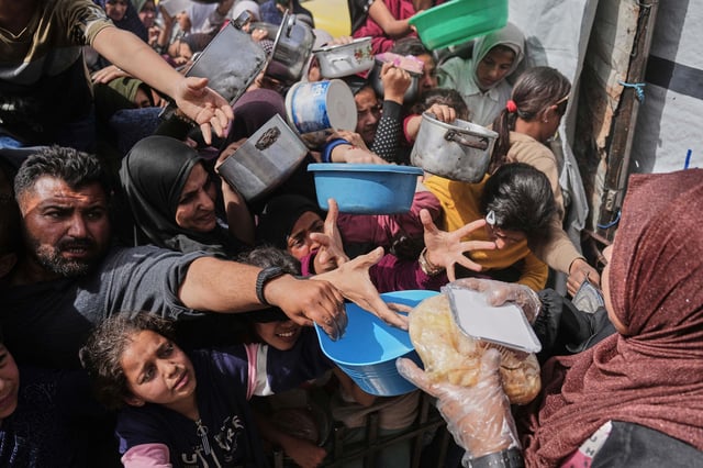 Palestinians clamber to receive donated food at a distribution center in Beit Lahiya in the northern Gaza Strip on April 7.