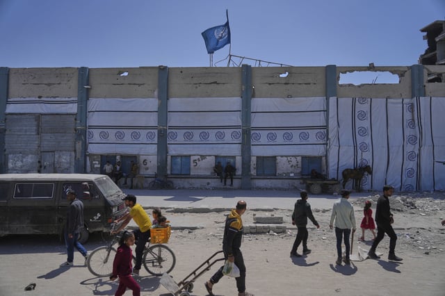 FILE - Palestinians walk next to the closed humanitarian aid distribution center of UNRWA, the U.N. agency helping Palestinian refugees in Jabaliya, Gaza Strip on Tuesday, April 29, 2025. (AP Photo/Jehad Alshrafi, File)