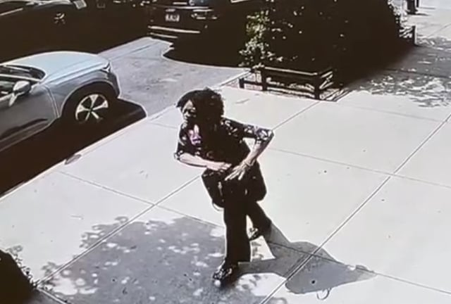 After the woman is grazed by the stray bullet, she walks down W. 131st St. while reaching into her purse for something, perhaps  her phone or a tissue to stop the bleeding. (Screengrab from video obtained by NY Daily News)