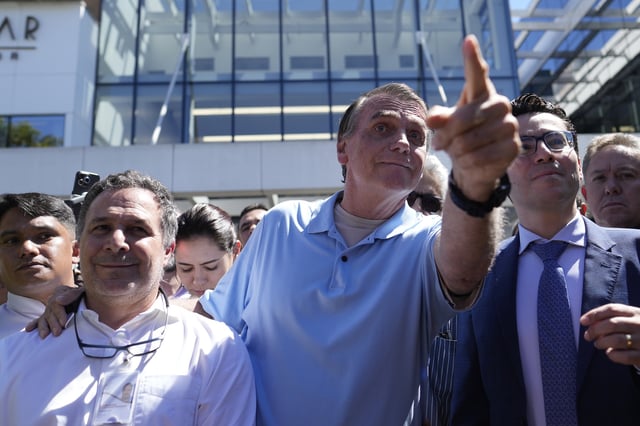 Former President Jair Bolsonaro points to supporters as he leaves the hospital after a weeks-long surgical stay, in Brasilia, Brazil, Sunday, May 4, 2025. (AP Photo/Eraldo Peres)