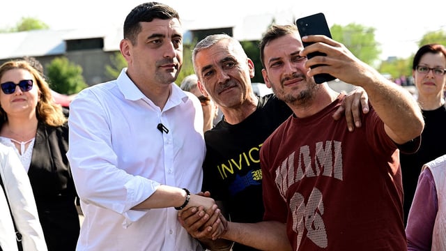 Presidential candidate George Simion shakes nahds and takes a selfie with supporters