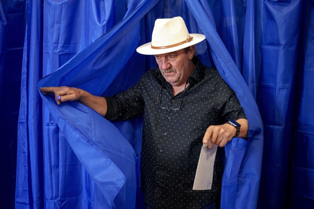 A man exits a voting booth before casting his vote in the first round of the presidential election redo in Bucharest, Romania, Sunday, May 4, 2025. (AP Photo/Andreea Alexandru)
