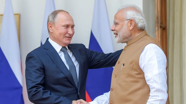 Prime Minister Narendra Modi shakes hands with Russian President Vladimir Putin.