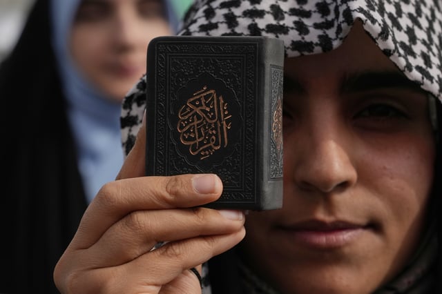 A demonstrator holds a copy of Islam's holy book, Quran, during a pro-Palestinian gathering in Tehran, Iran, Friday, May 2, 2025. (AP Photo/Vahid Salemi)