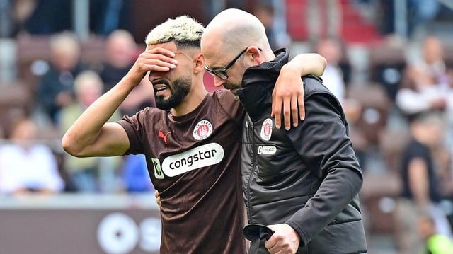 Elias Saad (l.) vom FC St. Pauli wird verletzt von Platz begleitet