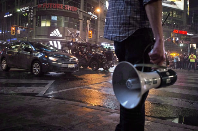 An assistant director stands by as a stunt car drives down Yonge Street in Toronto during the shooting of the movie 'Suicide Squad, on May 26, 2015. Canadian producers say spending on film and TV productions leapt by a record 28 per cent during the second year of the pandemic.